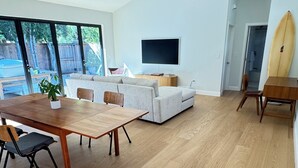 Ein geräumiges Wohnzimmer mit einem Holzesstisch, einer Couch und einem Fernseher.