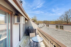 A balcony with a table and chairs, an air conditioning unit, and a covered grill. - Cozy 3BR Condo - Fireplace - Tannersville (Pennsylvania)