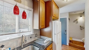 A kitchen with wooden cabinets, a stainless steel sink, and a white refrigerator. - Cozy 3BR Condo - Fireplace - Tannersville (Pennsylvania)