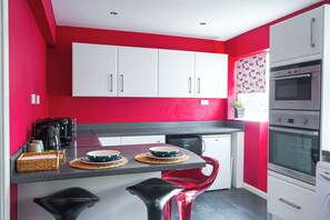 A kitchen with white cabinets, a red wall, and a built-in oven. - Perfect for Professionals,Visitors &Extended Stays near Qmc,Warhammer,University (Nottingham)