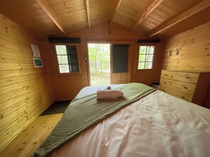 A wooden cabin room with a bed, two windows, and a view of the outdoors. - Spacious Lodge @Madawaska |Ideal for Groups|Trails (Lake Saint Peter)
