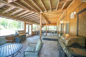A covered outdoor area with wooden beams, a grill, tables, and chairs. - Spacious Lodge @Madawaska |Ideal for Groups|Trails (Lake Saint Peter)