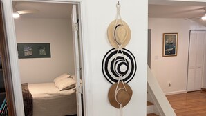 Una stanza con un letto, una scala e un muro decorato con cappelli.