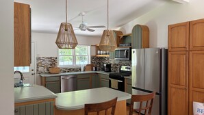 Una cucina moderna con mobili in legno, un'isola centrale, elettrodomestici in acciaio inossidabile e una ventola a soffitto.