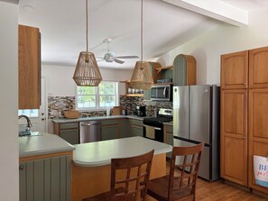 Eine moderne Küche mit Holzausstattung, einer zentralen Kochinsel, Edelstahlgeräten und einem Deckenventilator.