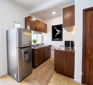 Eine moderne Küche mit Edelstahlgeräten, Holzschränken, einer Granitarbeitsplatte und einem gerahmten Kunstwerk an der Wand.
