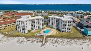 Ein Strandhotel mit mehreren Hochhäusern, einem zentralen Pool und einem Strand im Vordergrund.