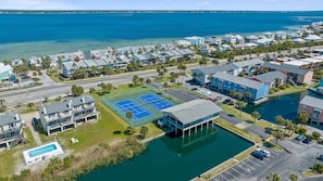 A coastal residential area with a tennis court, a swimming pool, and a marina.