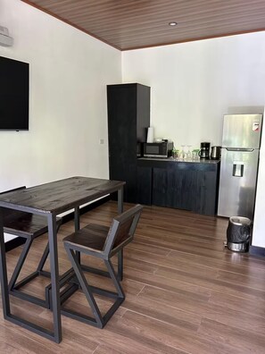 Eine moderne Küche mit Essbereich, einer Mikrowelle, einer Kaffeemaschine und einem Kühlschrank.
