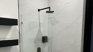 A modern bathroom with a glass-enclosed shower, a toilet, and a wooden floor. - Duke's Place 2 (Quepos)