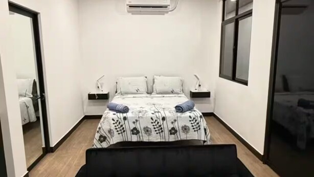 A modern room with a black sofa, a bed with a floral bedspread, and a wooden ceiling. - Estudio Duke´s Place n.º 6 (Quepos)