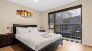 Une chambre à coucher avec un lit, une table de chevet, une fenêtre et une vue sur l’extérieur.