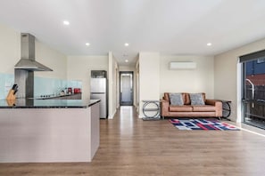 A modern kitchen with a central island, a brown leather sofa, and a patterned rug.