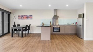 Une cuisine moderne avec un coin repas, un grand îlot central et une vue sur le paysage urbain.