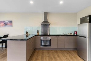 A modern kitchen with a central island, built-in oven, stainless steel appliances, and a minimalist design.