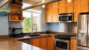 A kitchen with wooden cabinets, a stainless steel refrigerator, a microwave, and a stove.