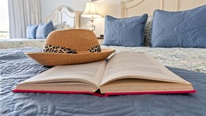 Ein Bett mit einem Buch und einem Strohhut darauf.