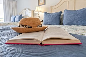 Ein Bett mit einem Buch und einem Strohhut darauf.