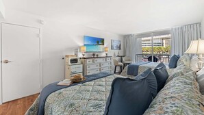 Ein Hotelzimmer mit Bett, Schreibtisch, Fernseher und Blick auf die Stadt.