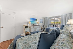 Ein Hotelzimmer mit Bett, Schreibtisch, Fernseher und Blick auf die Stadt.
