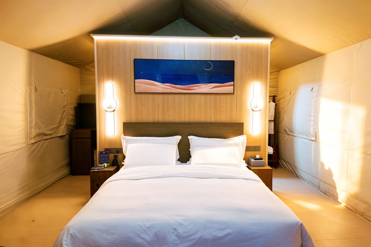 Um quarto tipo tenda acolhedor e bem iluminado, com uma cama grande, um mural com céu noturno na parede e duas luminárias de cabeceira.