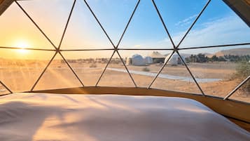 A tent with a view of a desert landscape and several yurts.