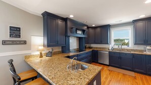 Una cocina moderna con armarios azul oscuro, encimeras de granito y un amplio ventanal con vistas.