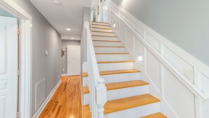 Una escalera con escalones de madera y barandillas blancas que conduce a un piso superior.