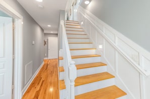 A staircase with wooden steps and white railings, leading to an upper floor. - Family Tree House | 2-Min Walk to Beach, Putting Green, Game Room & Large Fenced Yard (Holden Beach)