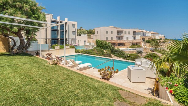 Um edifício moderno com piscina, área de estar externa e vista para o mar.