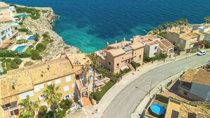 Uma área residencial costeira com edifícios, uma estrada e vista clara para o mar.