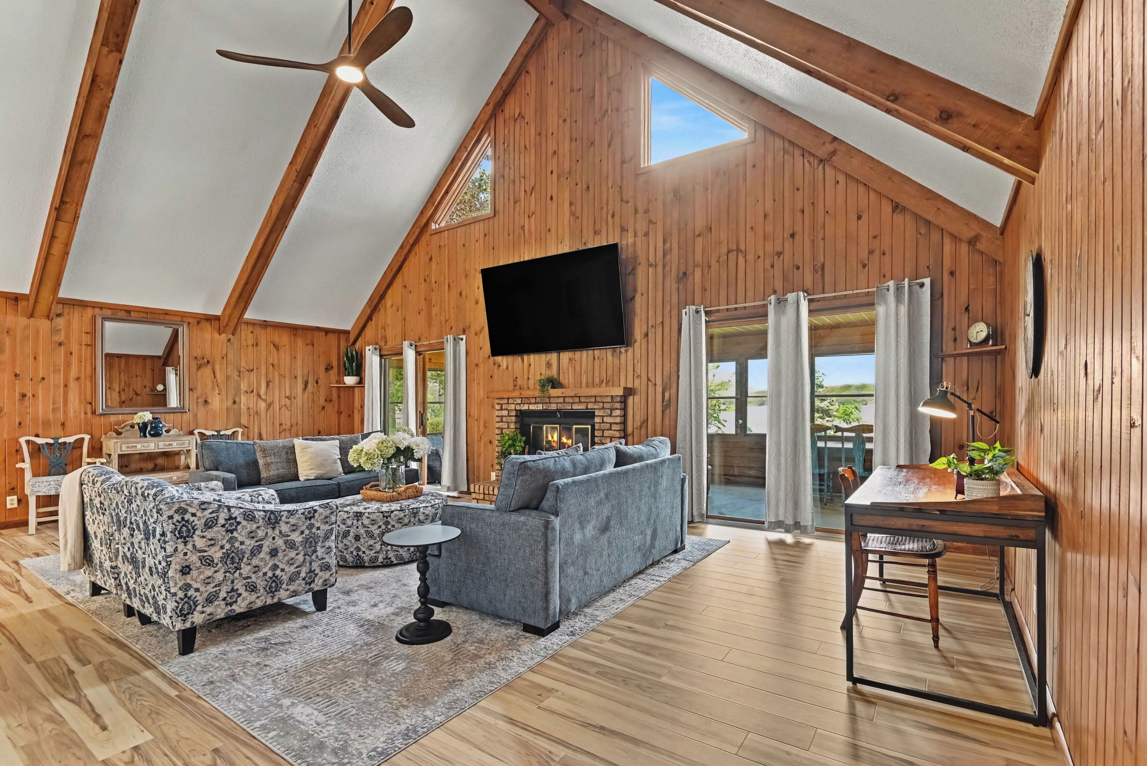A spacious loft with a high ceiling, wooden walls, a fireplace, a flat-screen TV, and a dining area.