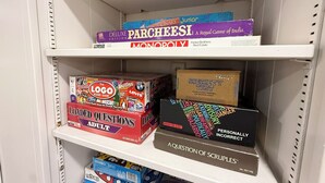 Hyllyssä on lautapelejä, kuten Monopoly, The Logo Board Game, Loaded Questions Adult ja A Question of Scruples.