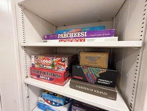 Ein Regal mit Gesellschaftsspielen, darunter Monopoly, Das Logo-Spiel, Loaded Questions für Erwachsene und A Question of Scruples.