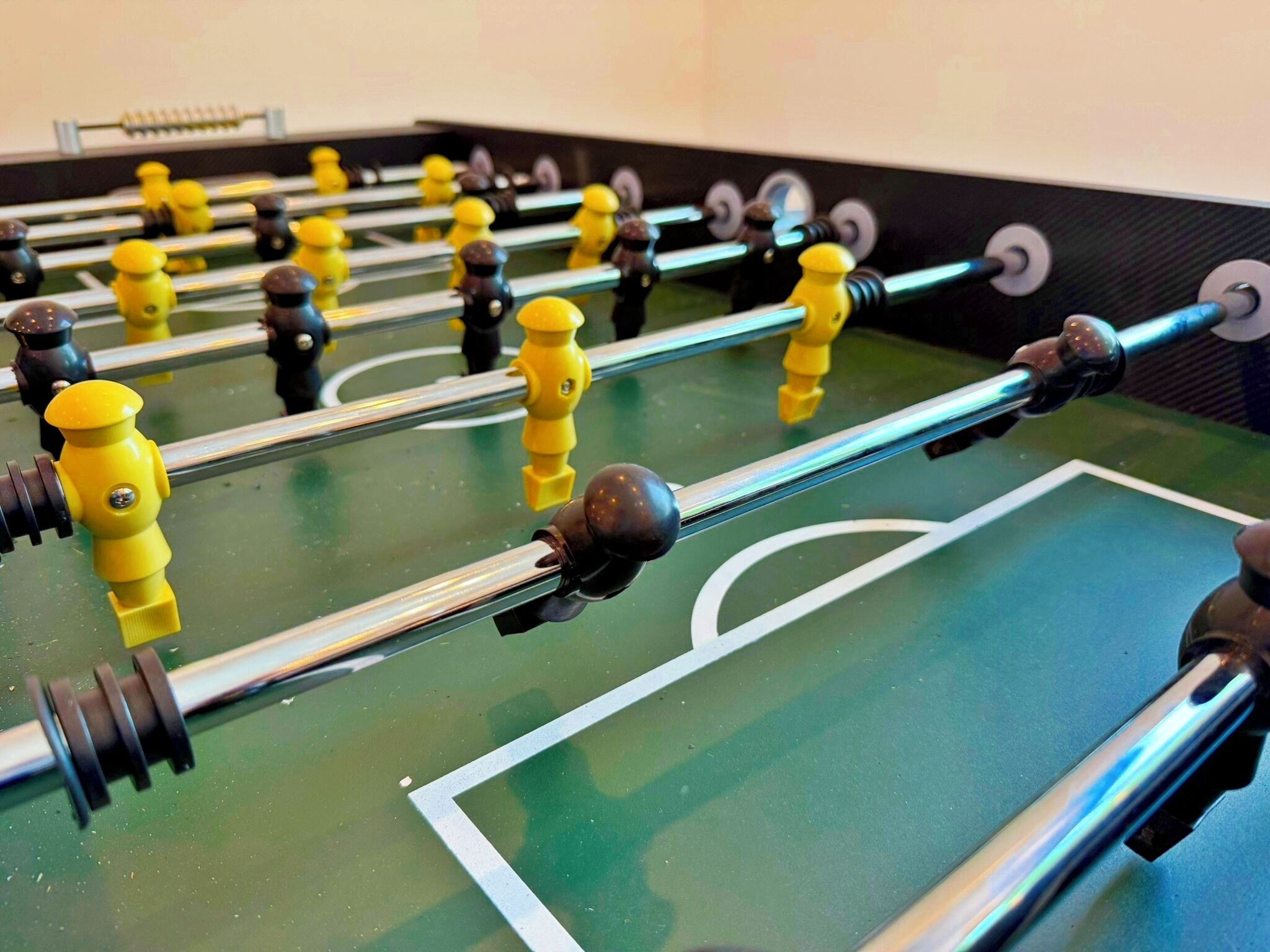 Una mesa de futbolín con barras de metal y figuras amarillas y negras.