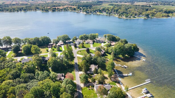 Ilmakuva järvenrantaisesta asuinalueesta, jossa näkyy taloja, veneitä ja laitureita.