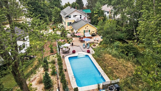 A residential property with a swimming pool, outdoor seating, and a view of a lake. - Tides of Saugatuck: Harbor Suite - Swimming Pool, Hot Tub, Koi Ponds (Saugatuck)