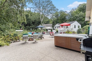 A patio area with outdoor seating, a hot tub, and a swimming pool.