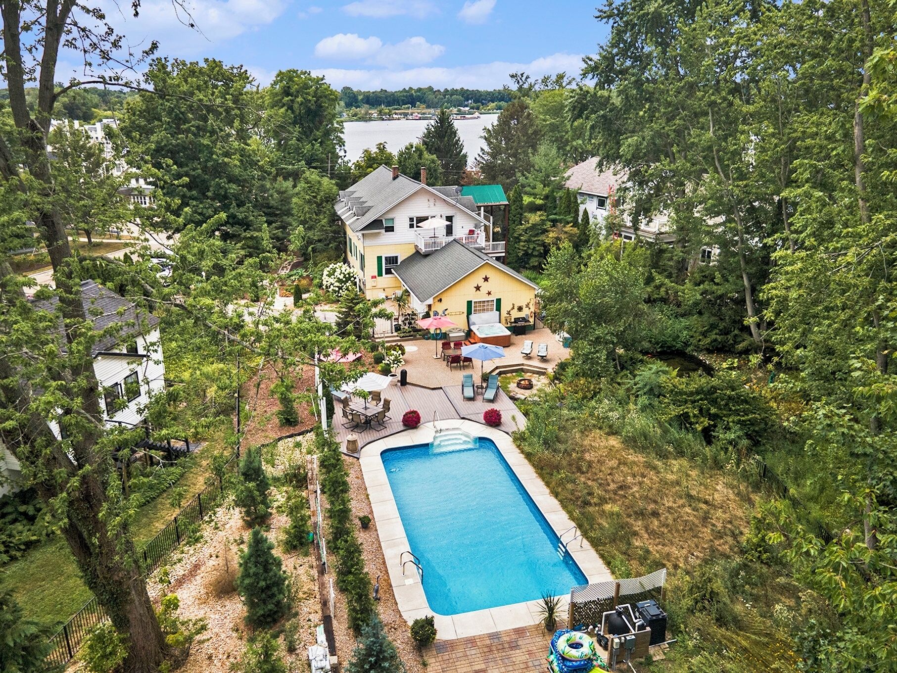 A residential property with a swimming pool, outdoor seating, and a view of a lake.