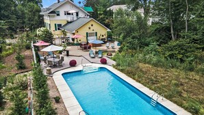 Ein rechteckiger Pool mit einer Sonnenterrasse, umgeben von Gartenmöbeln und einem überdachten Patio.