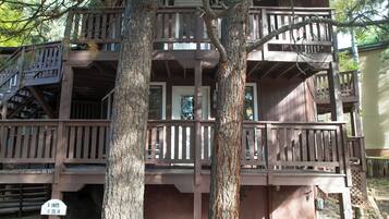 A multi-story wooden structure with balconies, a staircase, and a sign indicating unit availability.