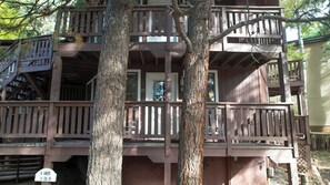 A multi-story wooden structure with balconies, a staircase, and a sign indicating unit availability. - Charming Cabin by the Lifts — Walk or Shuttle in Minutes (Angel Fire)