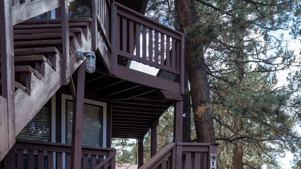 Una scala di legno conduce a una terrazza, con un albero nelle vicinanze.