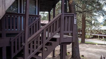 Un escalier en bois mène à une terrasse, et un arbre se trouve à proximité.