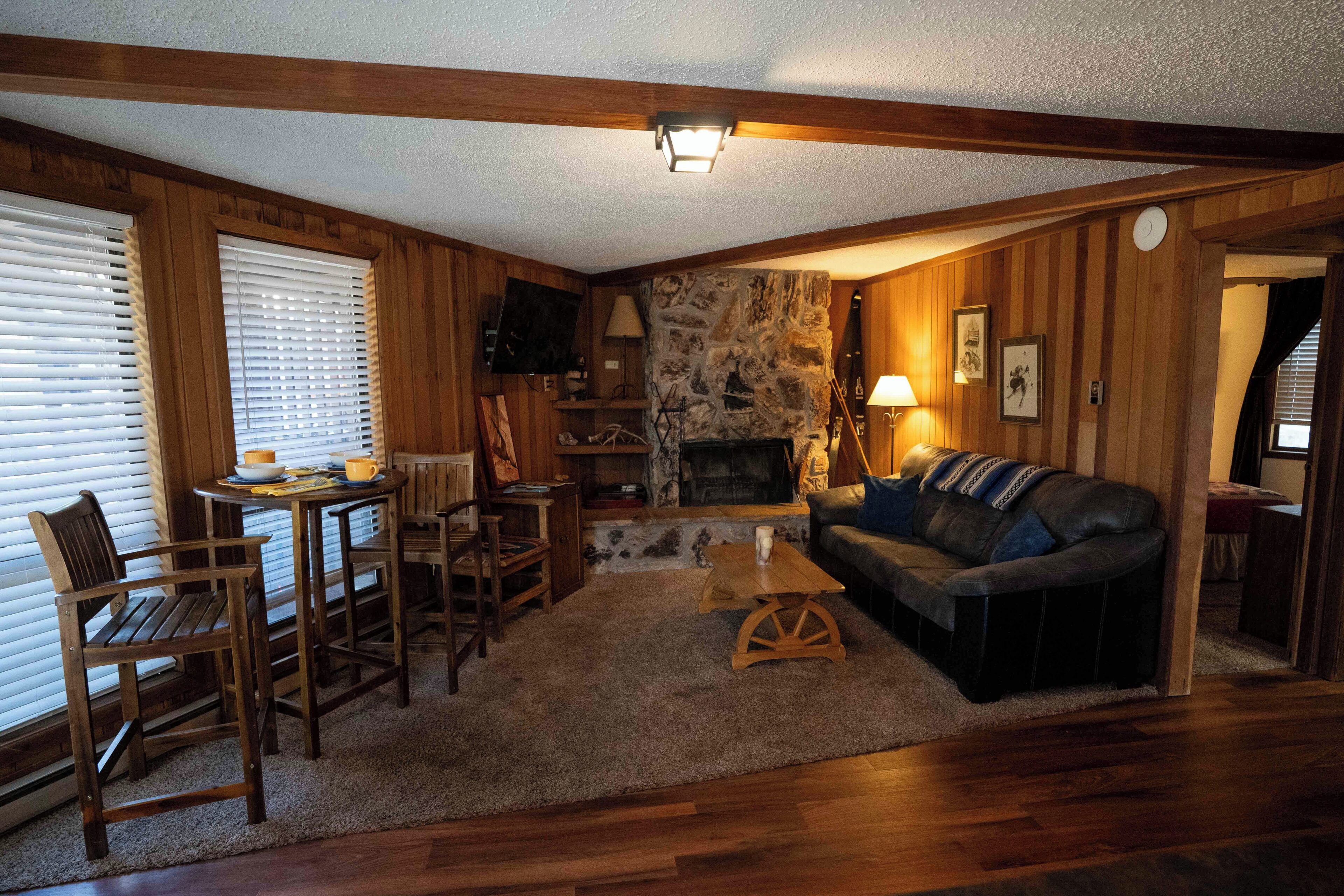 Un salon chaleureux avec des murs en bois, une cheminée en pierre, un canapé en cuir et une table basse en bois.