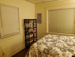 Ein Schlafzimmer mit floralem Bettbezug, einer Holzkammer mit verschiedenen Gegenständen und einem motivierenden Zitat an der Wand.