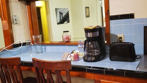 Ett kök med ett träbord, stolar, en kaffebryggare och en klocka på väggen.
