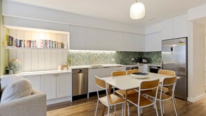 Een moderne keuken met witte kasten, een ruitjesachterwand, een ingebouwde vaatwasser en een roestvrijstalen koelkast.