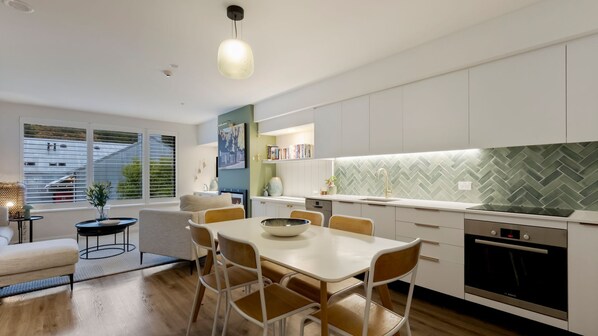 A modern kitchen with white cabinets, a herringbone backsplash, and a Bosch oven. - Apres Escape - 2 Bed (Queenstown)