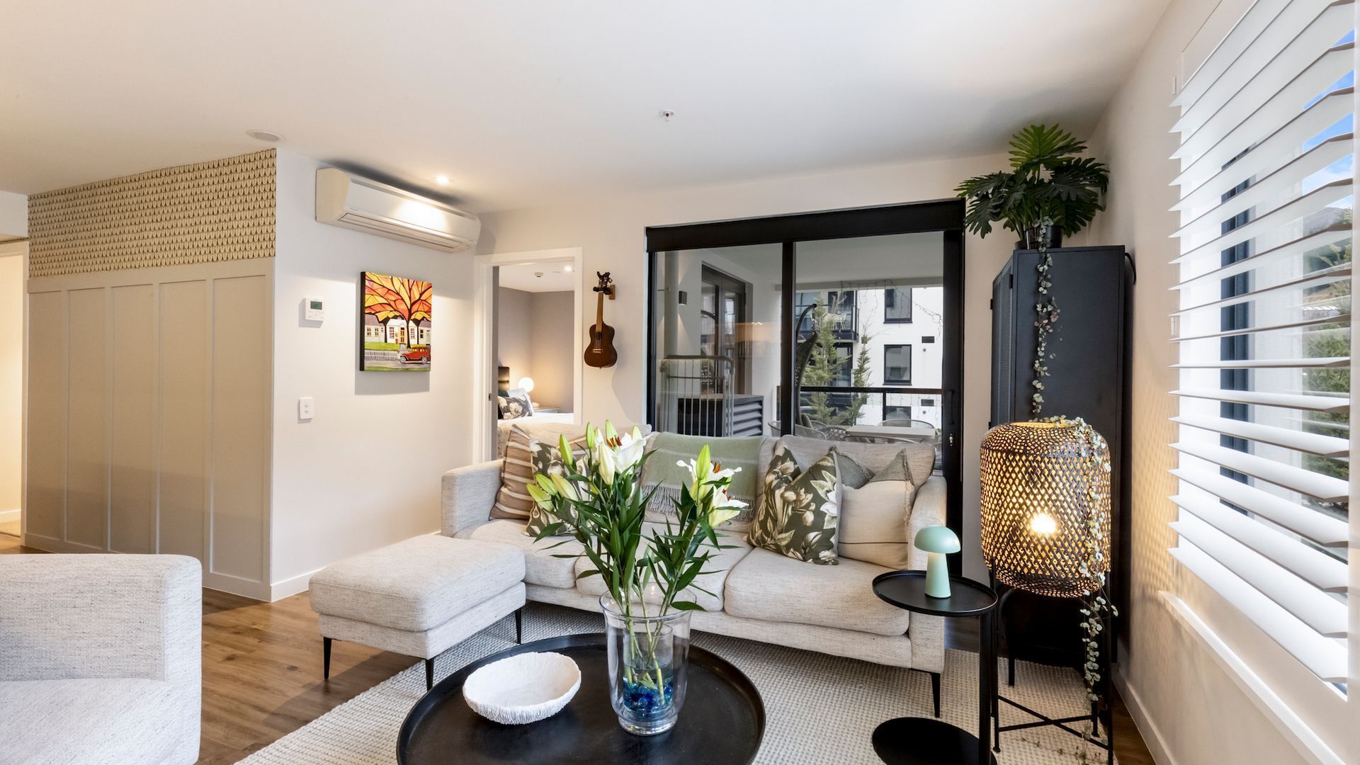 A modern living room with a sofa, coffee table, and decorative plants.